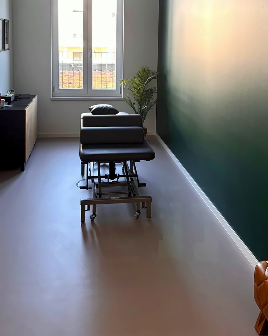Behandlungsraum mit Therapieliege und grüner Wand